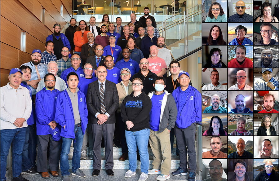 Group photo of half of IT Department staff on Campus Center staircase while the other half is remote. Some are wearing blue IT jackets and baseball hats.