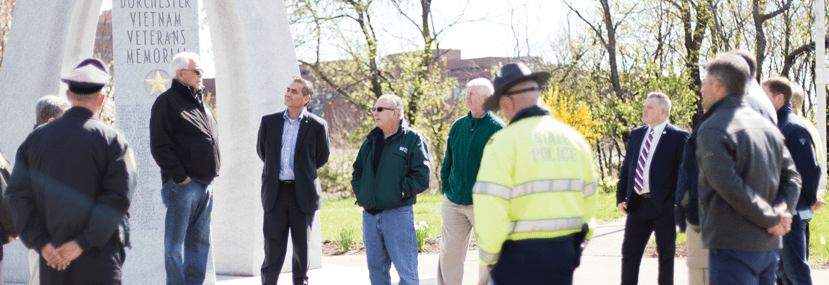 City Councilor Frank Baker and members of the memorial committee, UMass Boston, and Eversource gather around the Vietnam Memorial on Morrissey Boulevard.